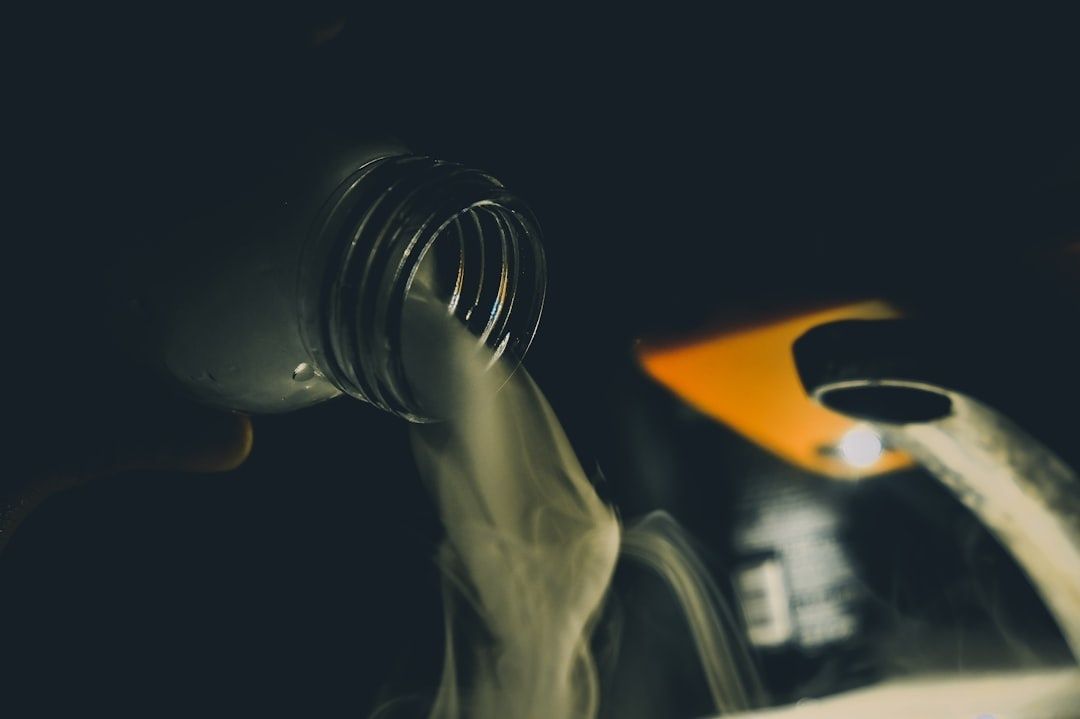 Motorolja hälls ur en flaska nära en bilmotor i mörker